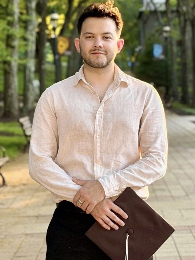 Justin Padgett on campus at Lehigh University holding a graduation cap