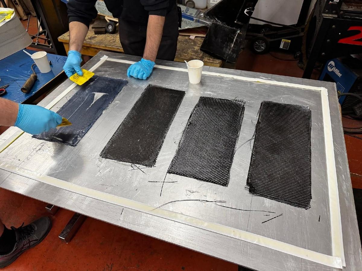 Wet layup in progress, epoxy being worked into the denim panel beside three carbon panels