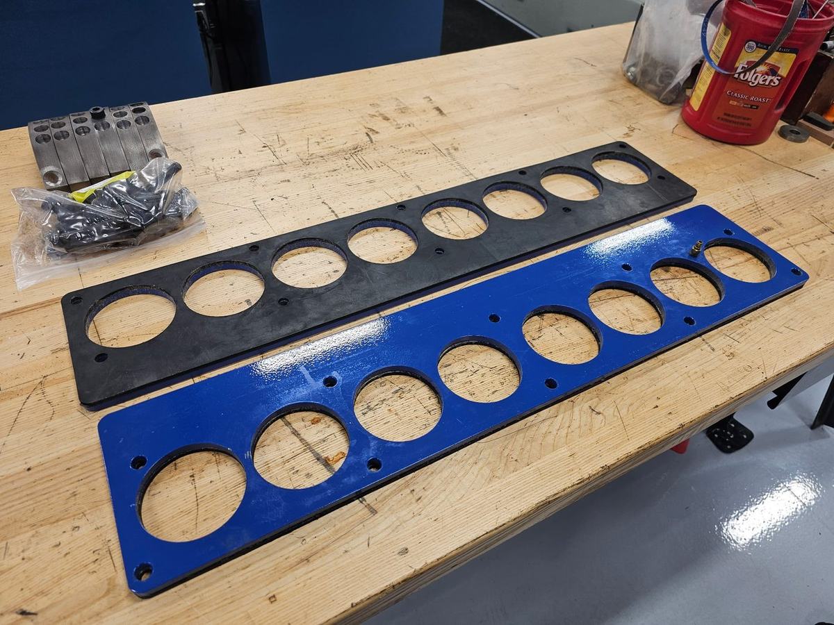 Pressure test plates with mounting hardware laid out on the bench