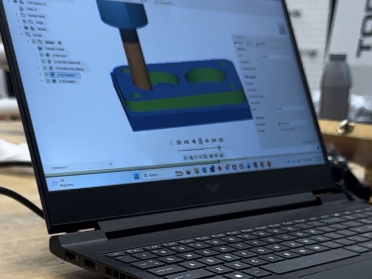 CAM toolpath programming on a laptop beside the machine