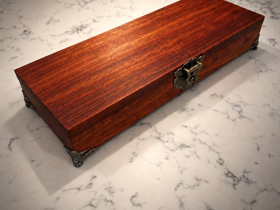 Padauk jewelry box closed, showing the brass latch and feet