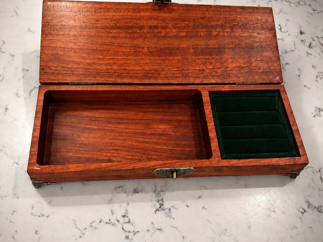 Jewelry box open, showing the velvet-lined ring slots and open compartment