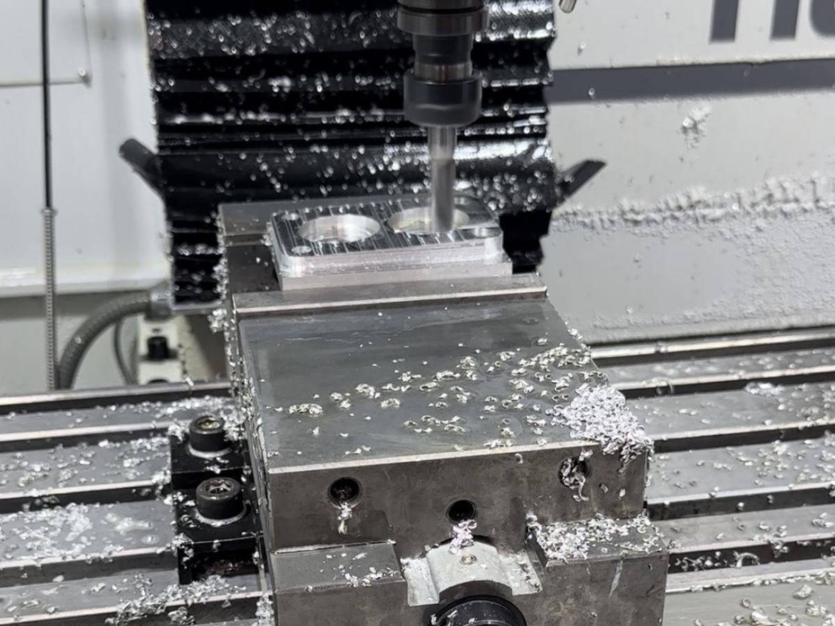Aluminum part being machined on a CNC mill under coolant