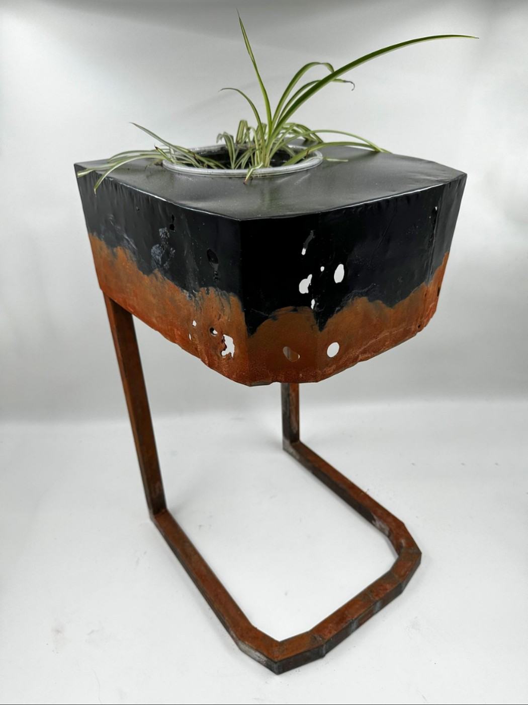 Cantilevered steel side table with integrated planter, black paint over a deliberate rust patina and pierced holes